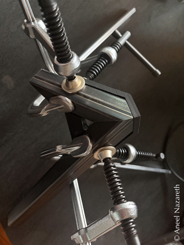 This picture looks like a space ship or some abstract art. Two steel tubes meet at a corner with a black plastic form holding them in place and clamps surrounding them